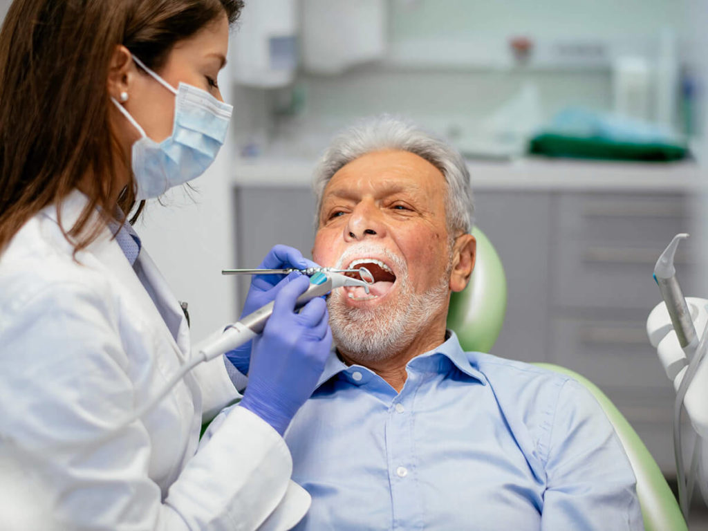 a senior-aged man, receiving care at the dentist