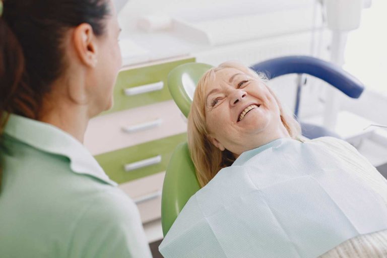 a senior aged woman sits at the dentist in the dental exam chair