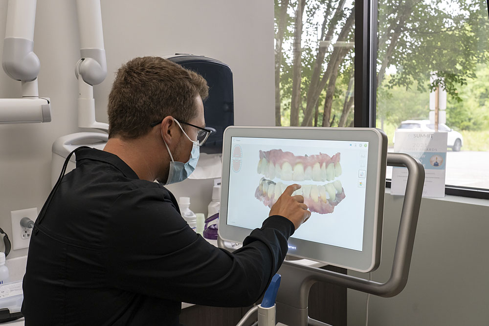 dentist pointing at a screen displaying a 3d model of teeth