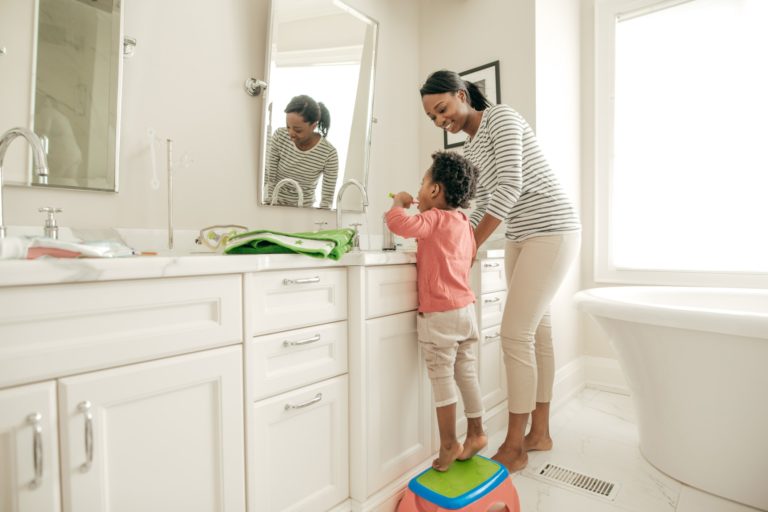 Image of mom and kid brushing teeth at the bathroom sink looking in the mirror, Summit Family Dentistry, Denver, North Carolina