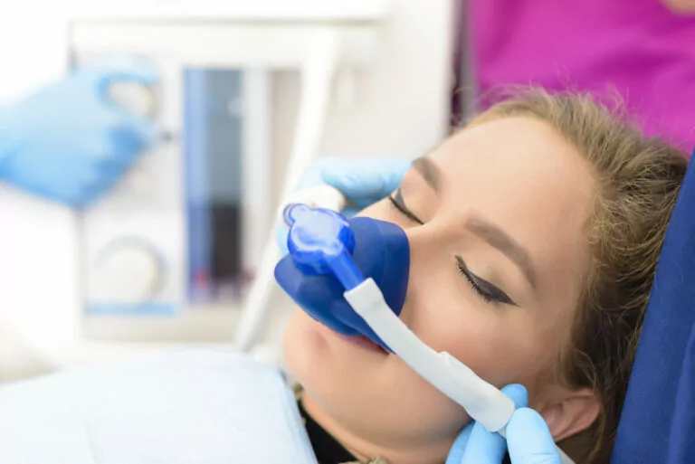 Stock image of a woman receiving sedation via an inhalation mask, at the dentist.